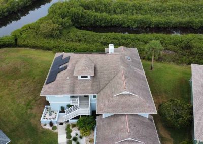 A rooftop installation of solar panels on a home with a scenic view of the surrounding greenery, including a river running nearby.