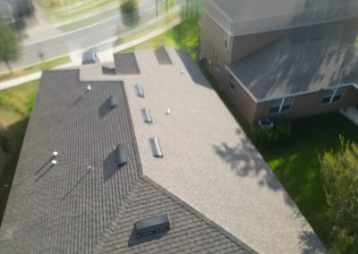 Top-down view of a residential roof with clear sections suitable for solar panel installation in a sunny suburban area.