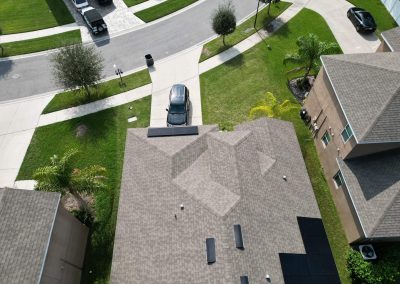 Aerial view of a house with a rooftop solar panel system installed, showcasing sustainable energy integration in a suburban neighborhood.