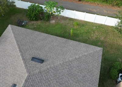 Aerial shot of a residential roof with clear space for potential solar panel installation, surrounded by a backyard with greenery.