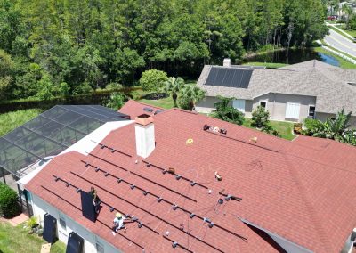 Workers placing solar panels on racks during installation by Smart Volt Solutions, with a green landscape in the background.