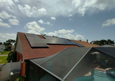 Full view of solar panels installed on a residential roof, with a screened patio and pool area visible in the foreground.